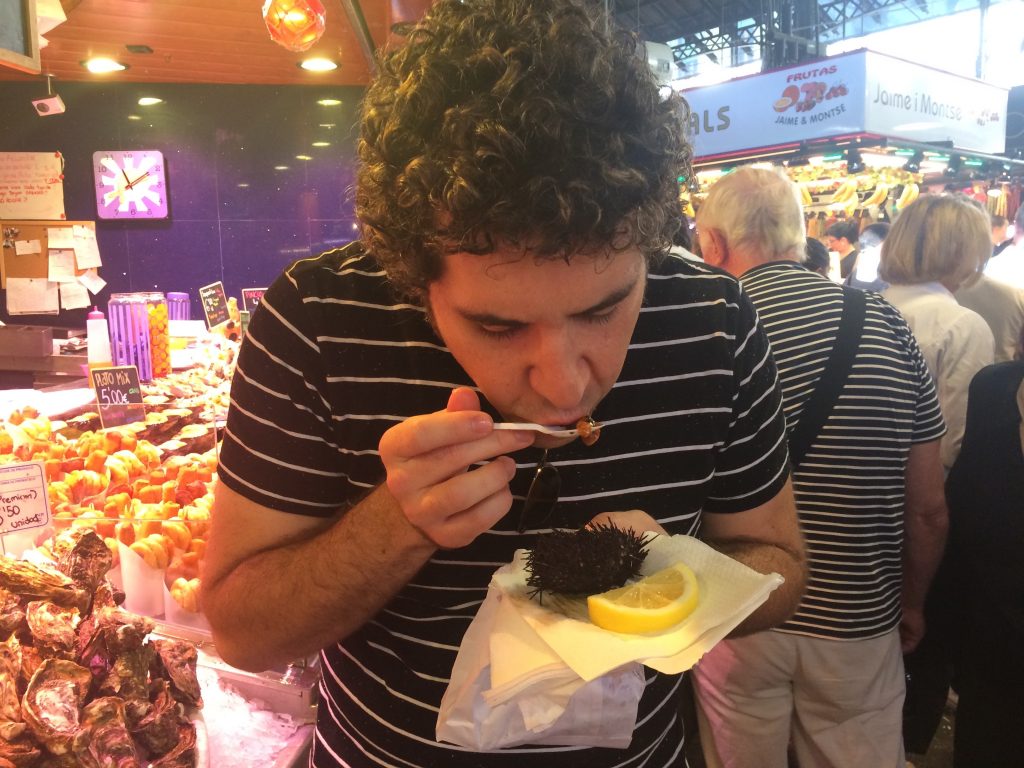 Eating a sea urchin with a bag of fried, shell-on shrimp in hand.